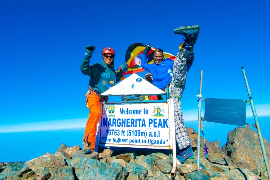 Climbers at the Margherita Peak summit sign, 5,109m and the highest point in Uganda, on the 9 Days Rwenzori Margherita Peak Trek
